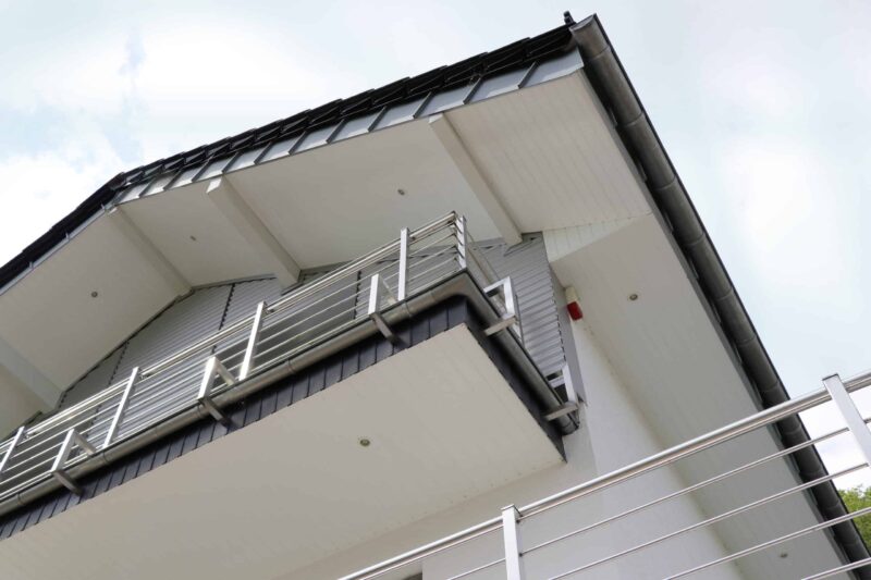 Weiße PVC Paneele 17/250 als Verkleidung an einem Balkon mit Edelstahlgeländer. Kunststoffpaneele für Fassade und Dachkasten.